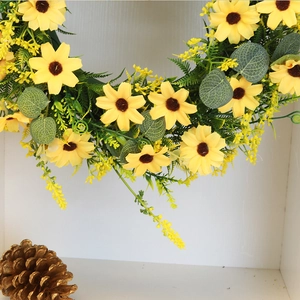 Artificial sunflower wreath with bright yellow petals, green eucalyptus leaves and golden pinecone