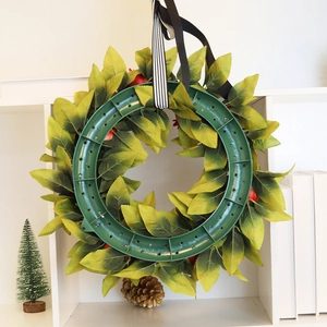 Detail view of the green plastic back structure and ribbon of a faux pomegranate wreath
