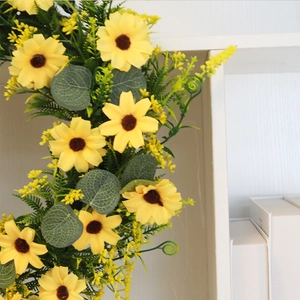 Detailed view of artificial sunflower wreath with yellow petals and green leaves