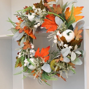 Autumn wreath with maple leaves, white pumpkins, and berries for home door wall decoration