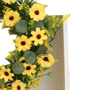 Vibrant sunflower wreath with yellow blossoms and green foliage on a minimalist stand