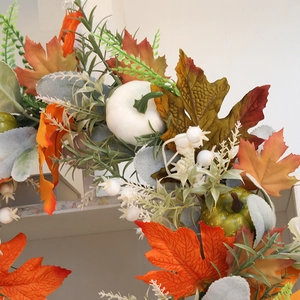 Close-up of autumn harvest wreath with orange maple leaves and white mini pumpkins