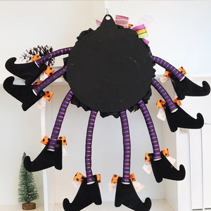 Halloween long leg witch decoration with purple striped legs and black boots on white wall