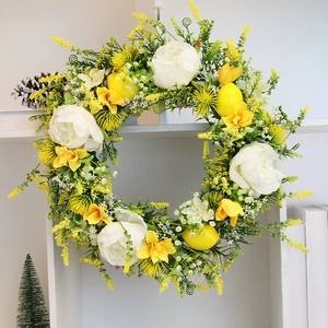 Close-up of artificial lemon wreath with white peonies and green leaves for home decor