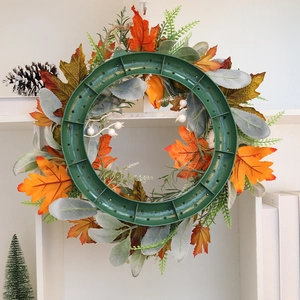 Harvest festival maple leaf wreath with white berries and pumpkins on a white shelf