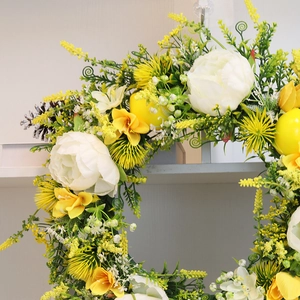 Artificial flower wreath with white peonies, yellow lemons and pine cones for front door decor