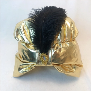 Dettaglio ravvicinato del turbante dorato metallizzato con piuma nera e gioiello ornato