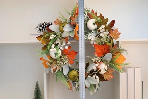 Detailed view of fall harvest wreath with maple leaves and pumpkins for home decor