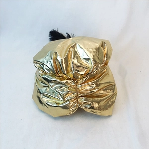 Dettaglio del turbante dorato con tessuto metallico plissettato e piuma nera decorativa