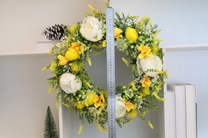 Detail showing artificial lemon wreath with white peonies and yellow flowers on a bookshelf