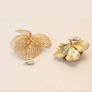 Golden artificial Christmas flower hair clips with textured leaves and silver metal fasteners