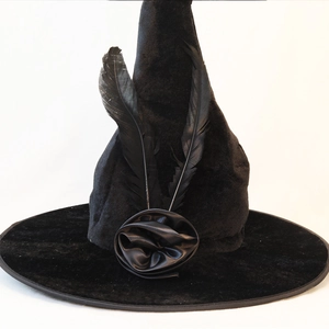 Detail of black velvet witch hat with elegant feathers and a satin rose decoration