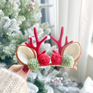 Détail d'une pince à cheveux bois de renne avec flocage rouge et petites boules de peluche