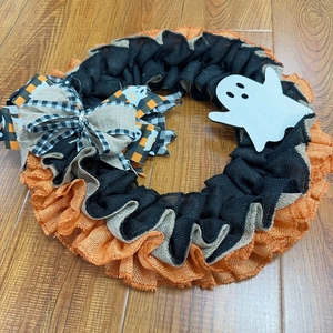 Detail of Halloween wreath featuring orange mesh layers and a white ghost wood cutout