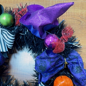Close-up of Halloween wreath featuring a purple wizard hat and orange pumpkin ornament
