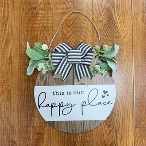 Rustic round wooden welcome sign with green foliage and striped bow for home wall decor