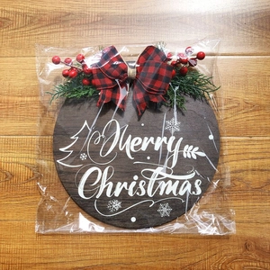 Round wooden Merry Christmas door sign with pine branches and red plaid bow decoration