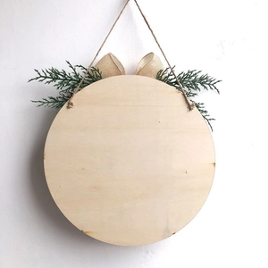 Weihnachtliches rundes Holztürschild mit Leinenschleife und Kiefernnadeln an der Wand