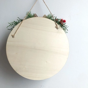 Close-up of circular wooden welcome sign with pine needles and red berries detail