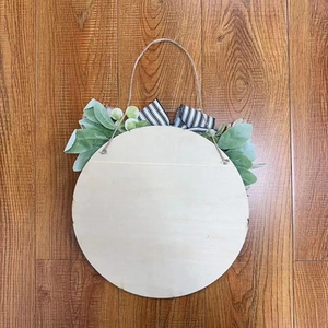 Detail of round wooden door sign with artificial greenery and striped bow on wood background