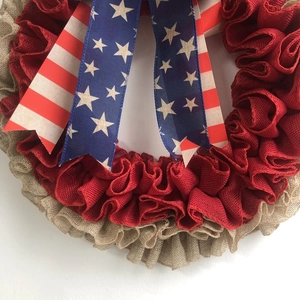 Détail d'une couronne en toile de jute rouge et beige avec rubans patriotiques