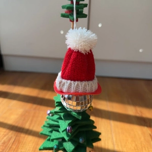 Close-up of a disco ball ornament with a red Christmas hat on a green felt tree