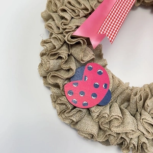 Handmade burlap door wreath featuring pink ribbons and a cute ladybug wooden ornament