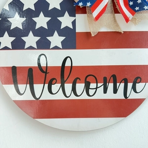 Round Independence Day wooden welcome sign with US flag design and burlap bow for home decor