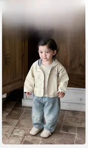 Detail of baby boy hooded jacket with dinosaur print and light blue denim jeans