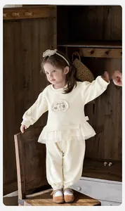 Détail du sweat-shirt crème pour bébé fille avec ourlet en dentelle et écusson animal