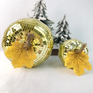 Close-up of golden disco mirror ball pumpkins with maple leaf for festive party decor