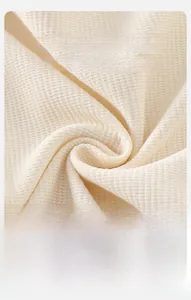 Détail macro du tissu en maille gaufrée douce pour ensemble bébé blanc cassé