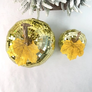 Close-up of golden disco mirror pumpkins with maple leaf for holiday party decor