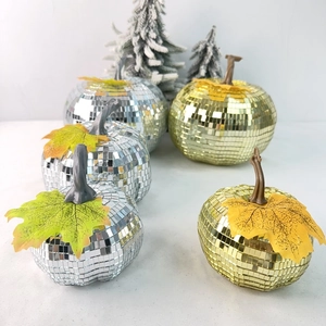 Close-up of mirror mosaic disco pumpkins in gold and silver with festive maple leaf detail