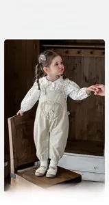 Détail de la blouse florale pour bébé fille avec col dentelle et salopette à cœur