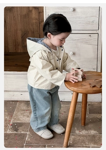Detail of baby boy beige hooded jacket and light blue wide-leg jeans in casual style