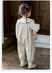 Détail du chemisier floral pour bébé avec col volanté et salopette en coton beige porté