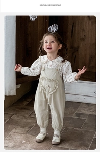 Détail de l'ensemble bébé avec salopette à volants cœur et chemise à col en dentelle