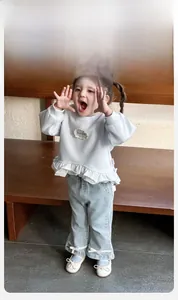 Detail of baby girl outfit showing ruffle hem sweatshirt and bow ribbons on denim pants
