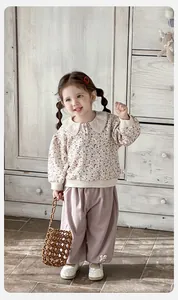 Detail of baby girl floral sweatshirt with lace collar and purple embroidered trousers