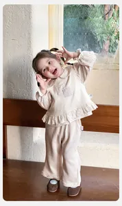 Vue détaillée d'un ensemble bébé fille beige en coton avec ourlet volanté et carreaux