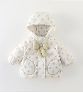 Détail d'une doudoune fleurie pour bébé avec un grand nœud vert et poches pelucheuses