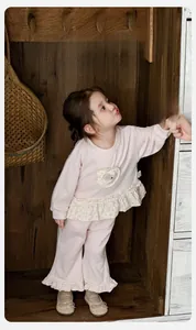 Close-up detail of pink toddler girl tracksuit with lace trim and soft cotton texture