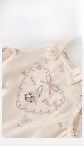 Gros plan sur la broderie lapin et le nœud rose d'une salopette en coton pour bébé