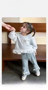 Close-up of baby girl blue sweatshirt with lace trim and denim jeans with silk bows