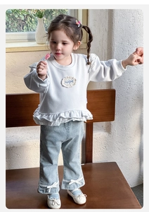 Detail of baby girl outfit with white lace sweatshirt and blue denim pants with bows