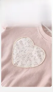 Detail of baby pink ribbed top with floral heart patch and lace trim, fluorescent free