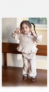 Détail d'un ensemble en tricot pour bébé fille avec col fleuri et pantalon large