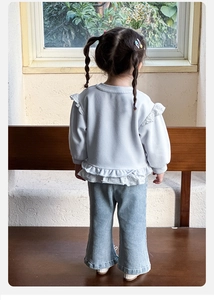 Rear view of girl in light blue sweatshirt with lace trim and matching denim wide-leg pants