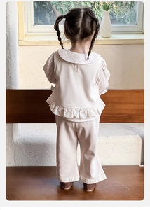 Détail de la tenue trois pièces pour bébé fille avec gilet en dentelle et chemise